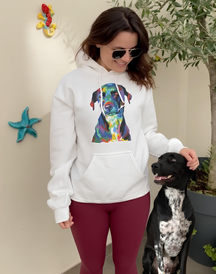 Woman wearing a white hoodie with a colorful dog graphic, standing next to a black and white dog indoors.