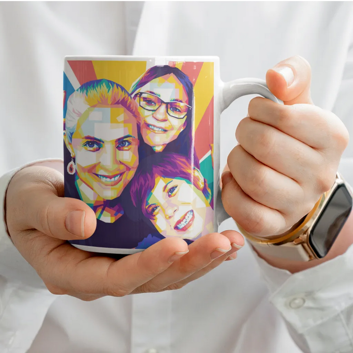 Person holding a mug with colorful design of three people's faces.