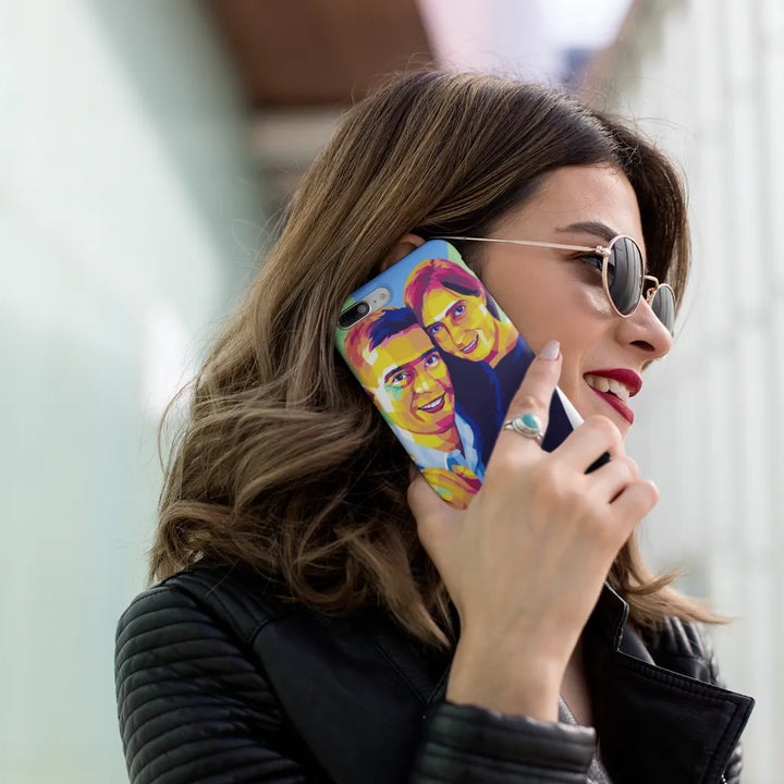 Woman holding a phone with a colorful case featuring two faces, wearing sunglasses.