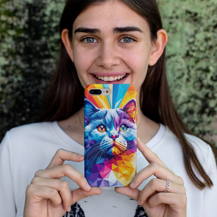 Person holding a colorful phone case with a cat design against a green leafy background