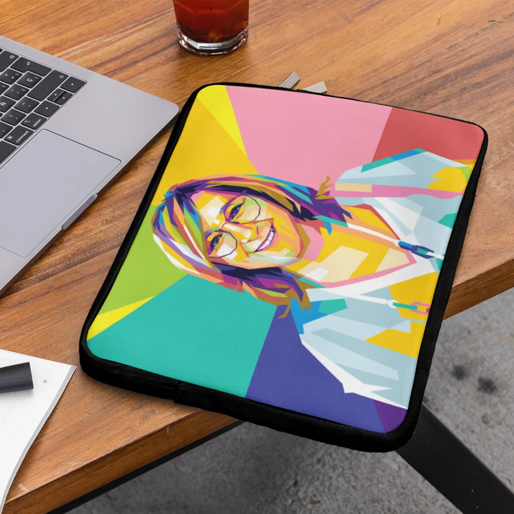 Colorful laptop sleeve with artistic design on a wooden table with a laptop and glass.