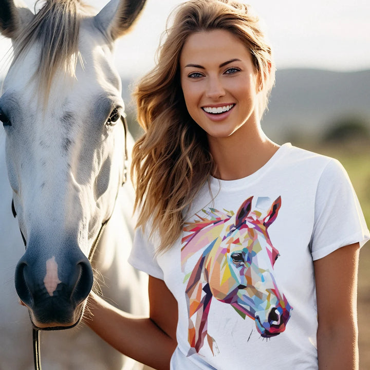 Woman wearing a white t-shirt with a colorful horse design, standing next to a white horse.
