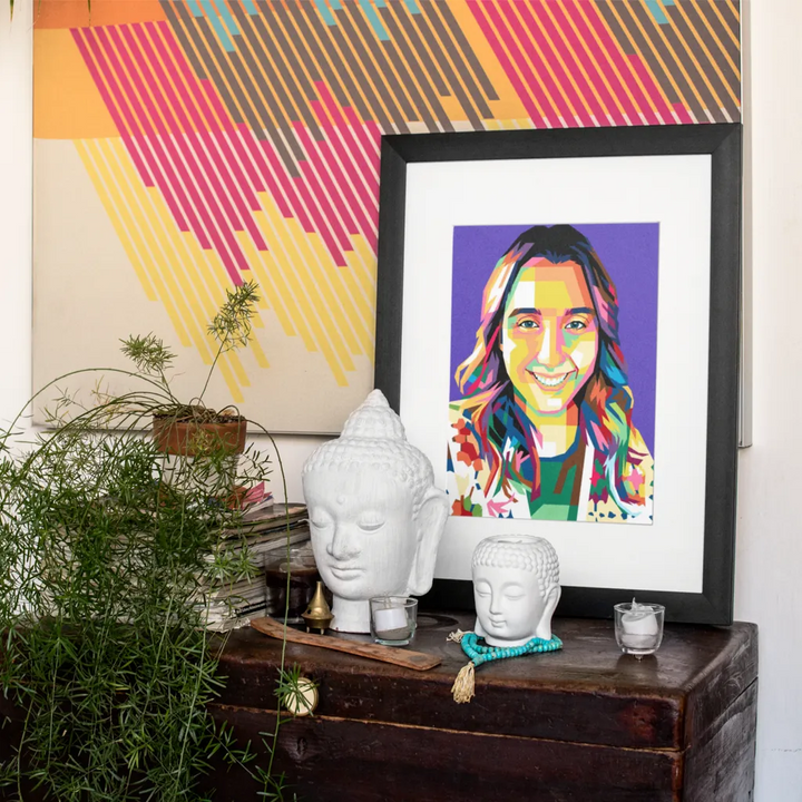 Framed colorful portrait on a wooden surface with decorative items and WPAP art in the background.